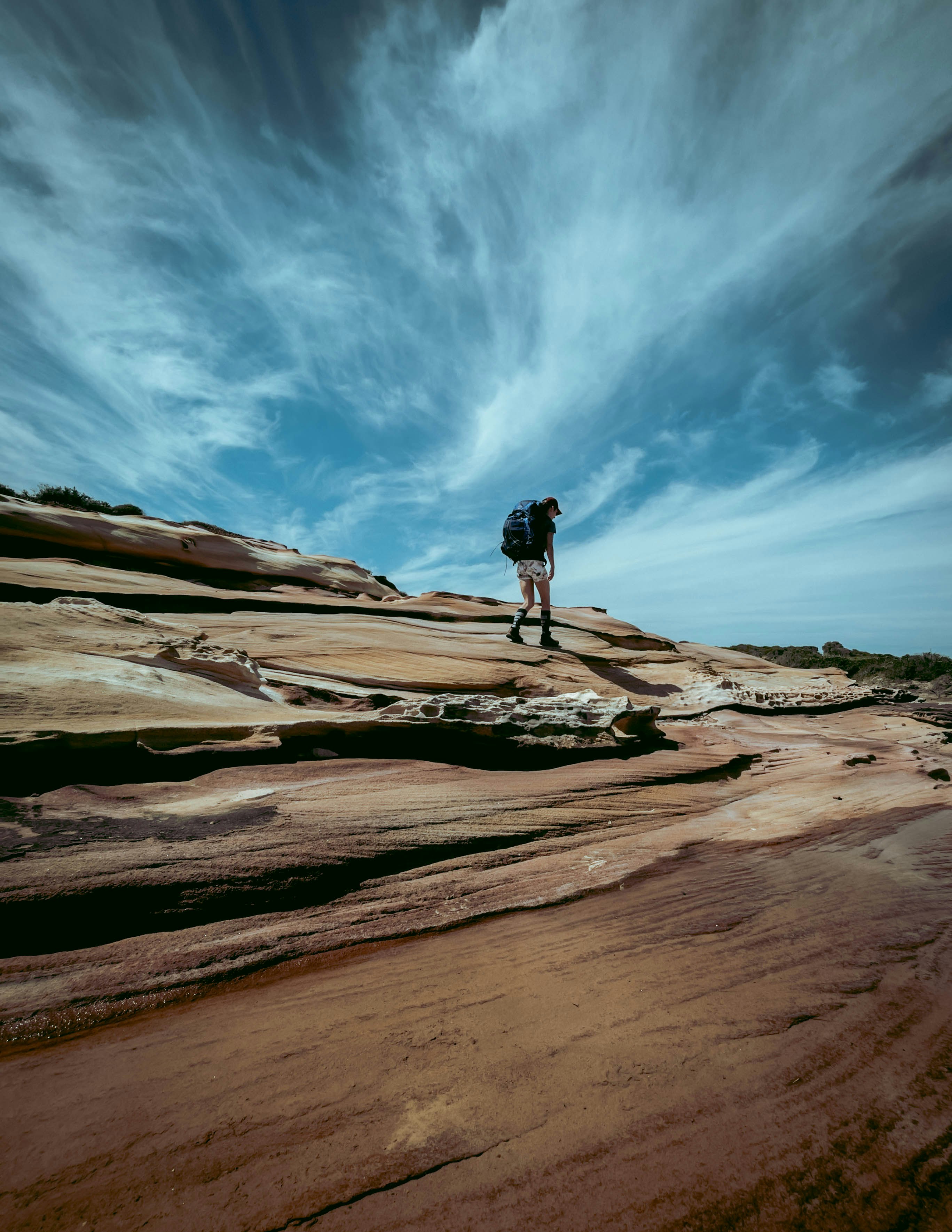 person standing on brown rock formation under blue sky during daytime